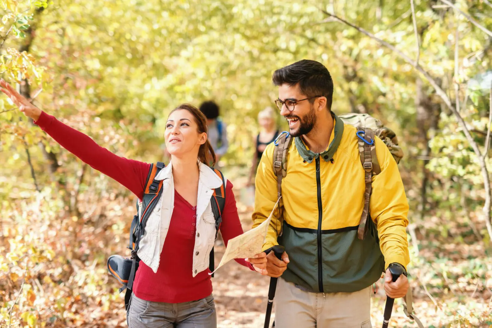 A man and woman walking in the woods holding hands.