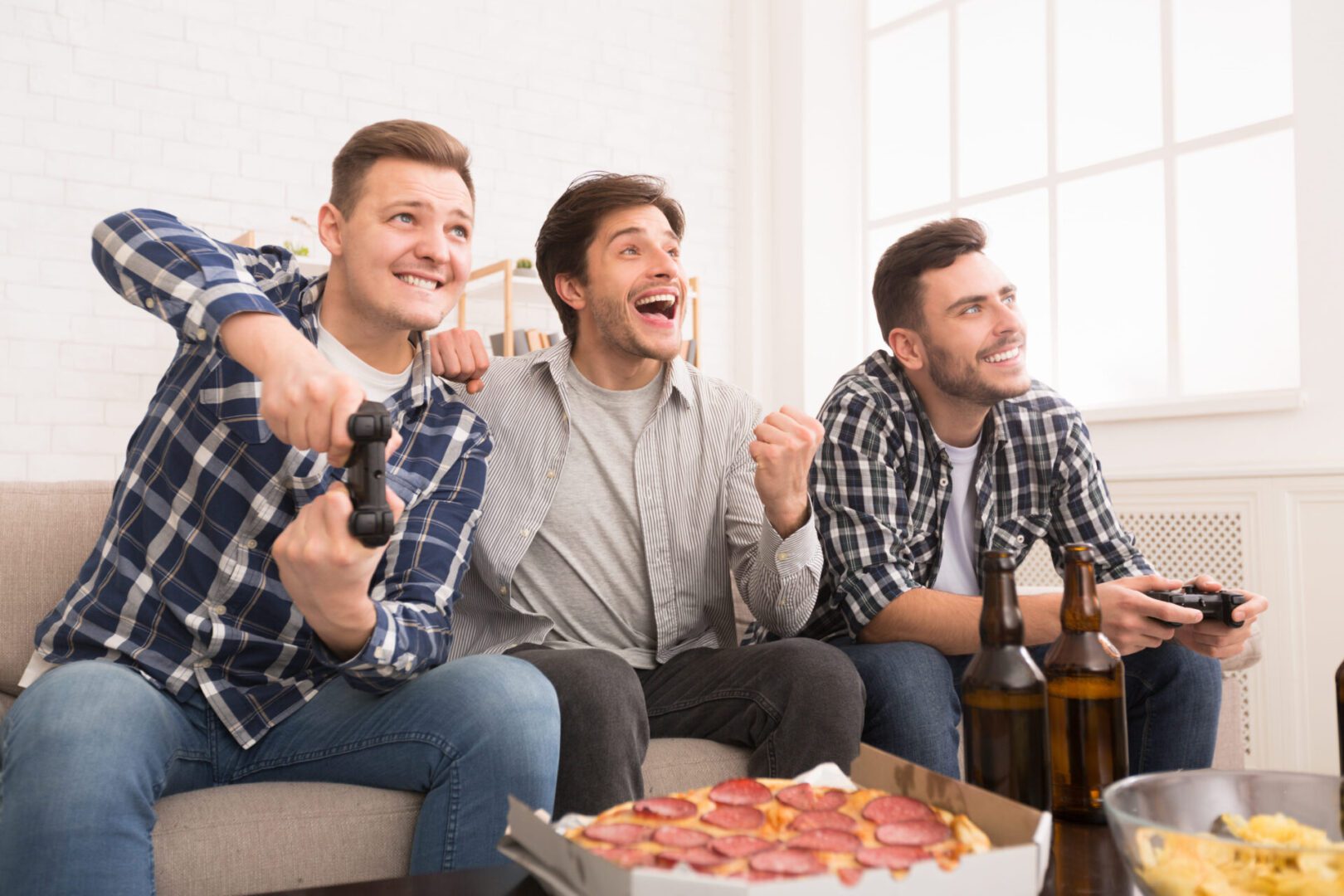 Three men sitting on a couch playing wii