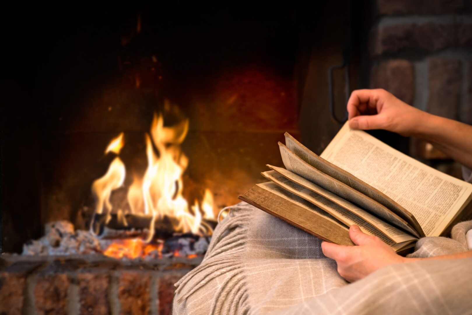 A person is reading by the fire