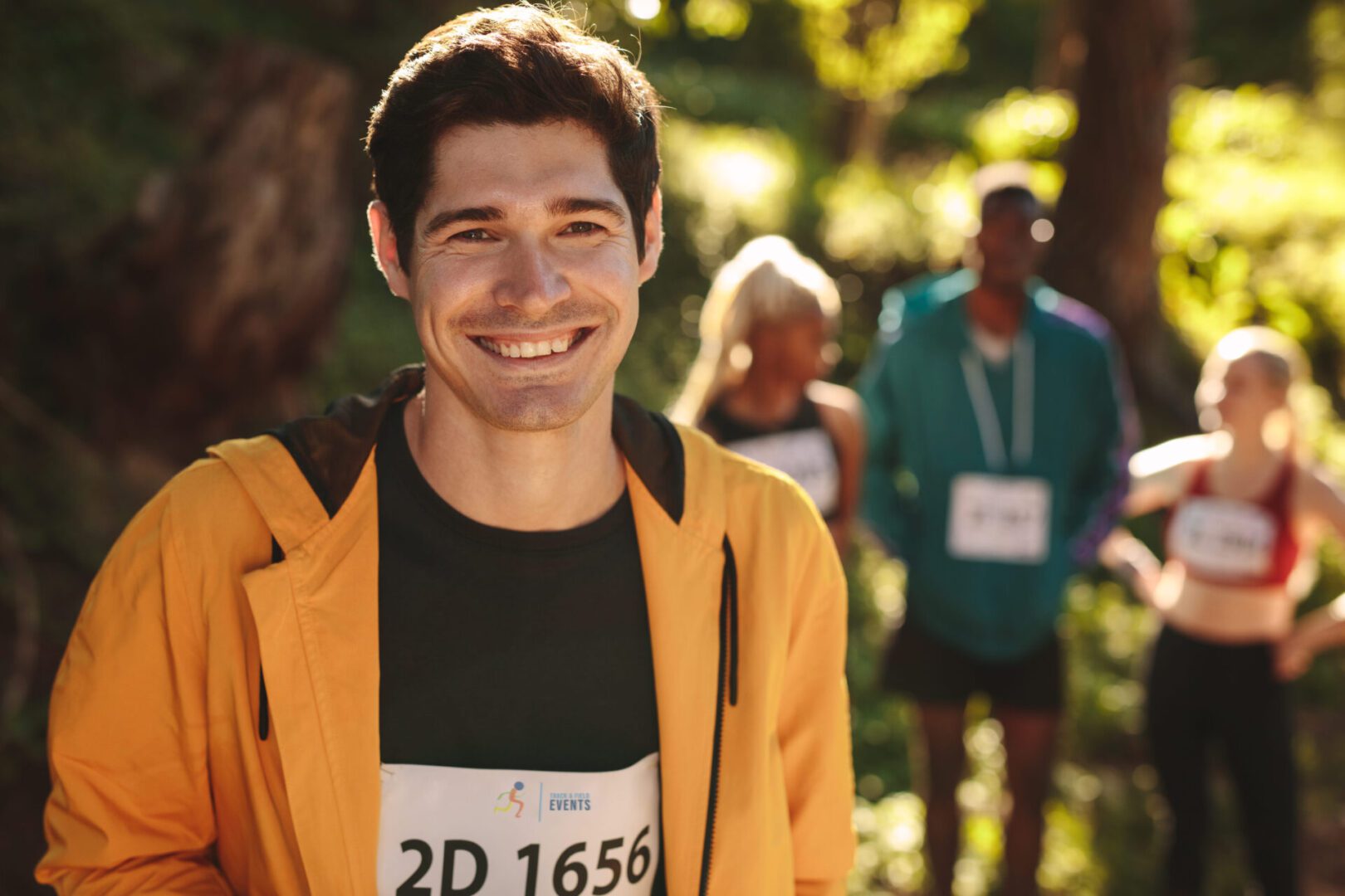 A man smiling while standing next to other people.