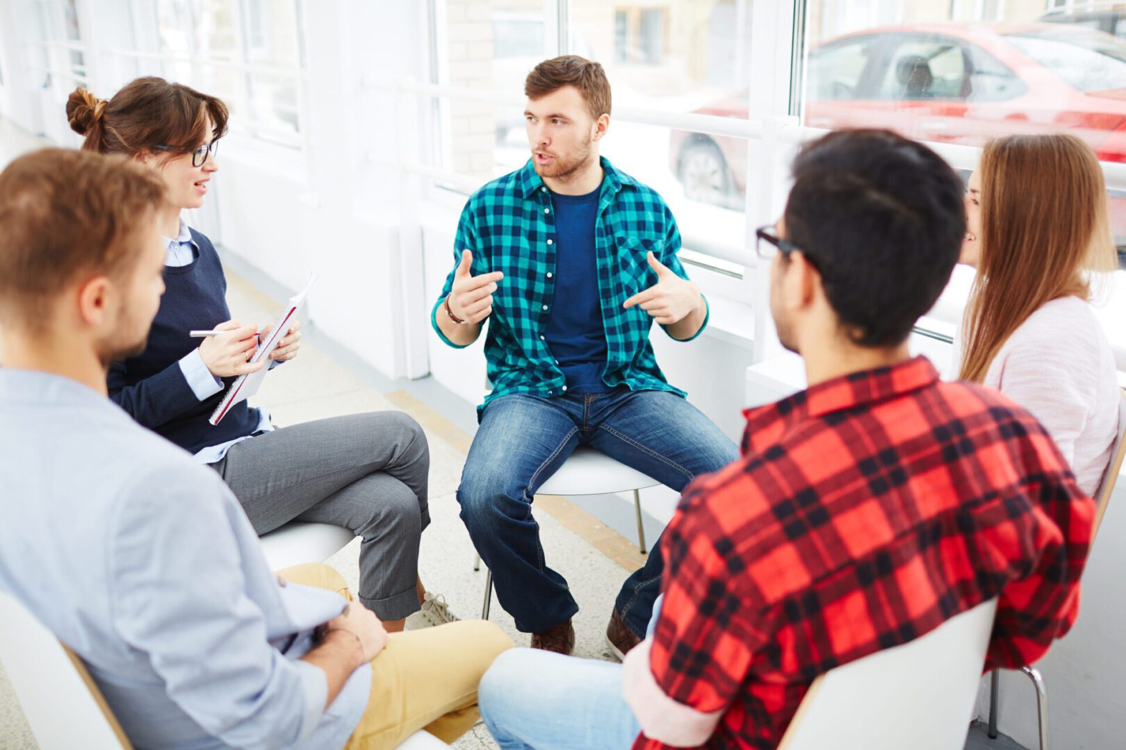 A group of people sitting in a circle talking to each other.