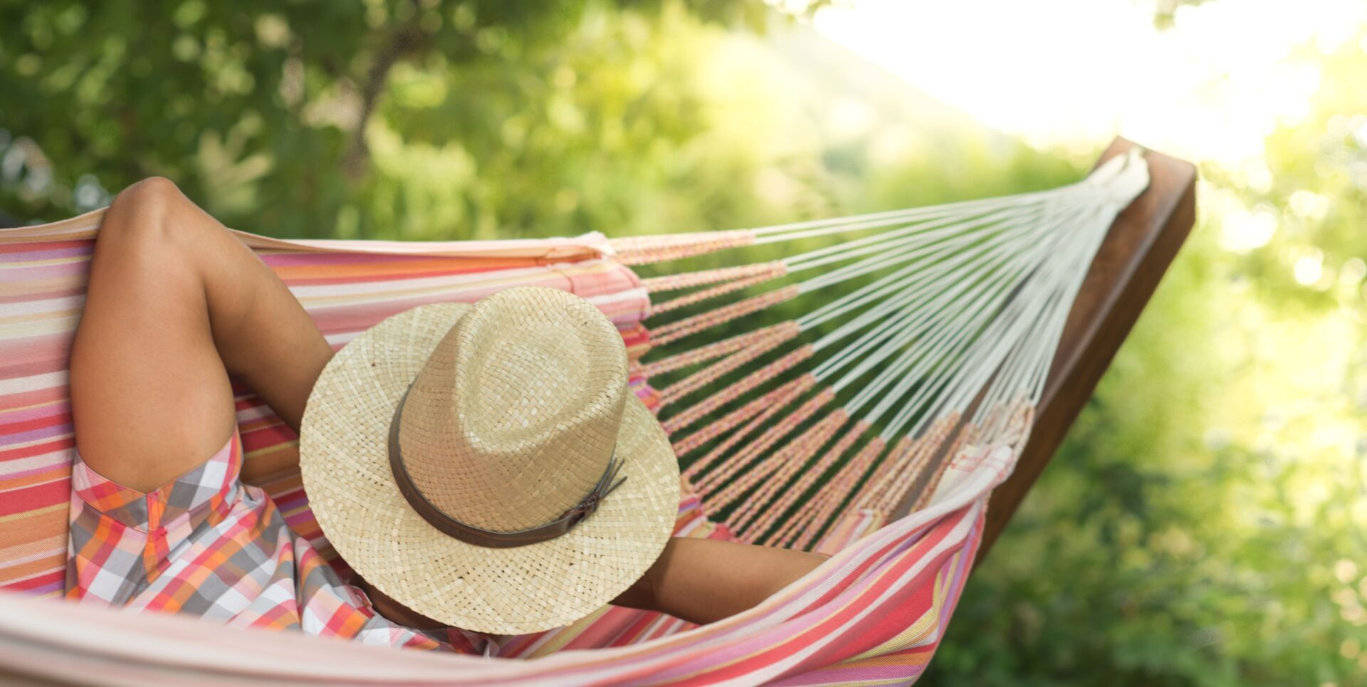 A person in a hammock with a hat and palm tree.