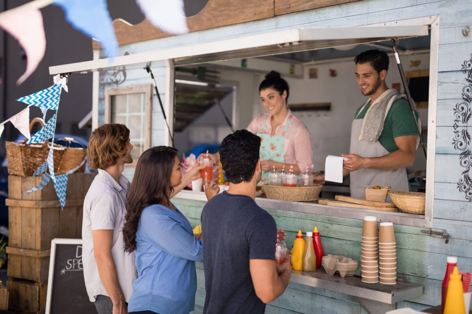 A group of people standing around a food stand.