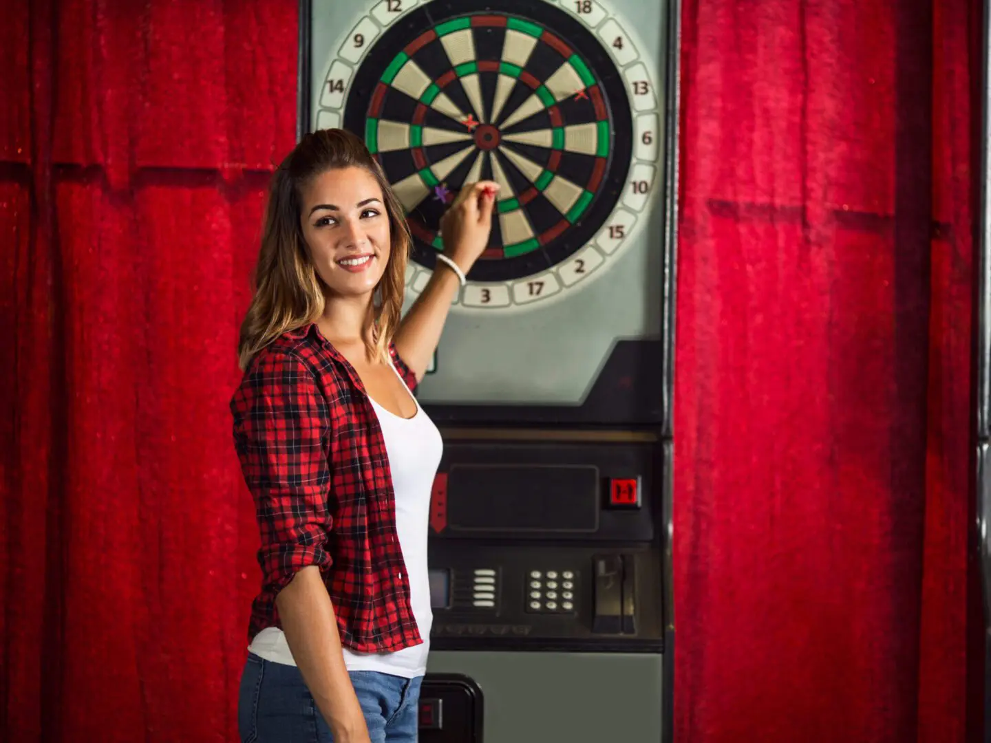 A woman standing in front of a dart board.