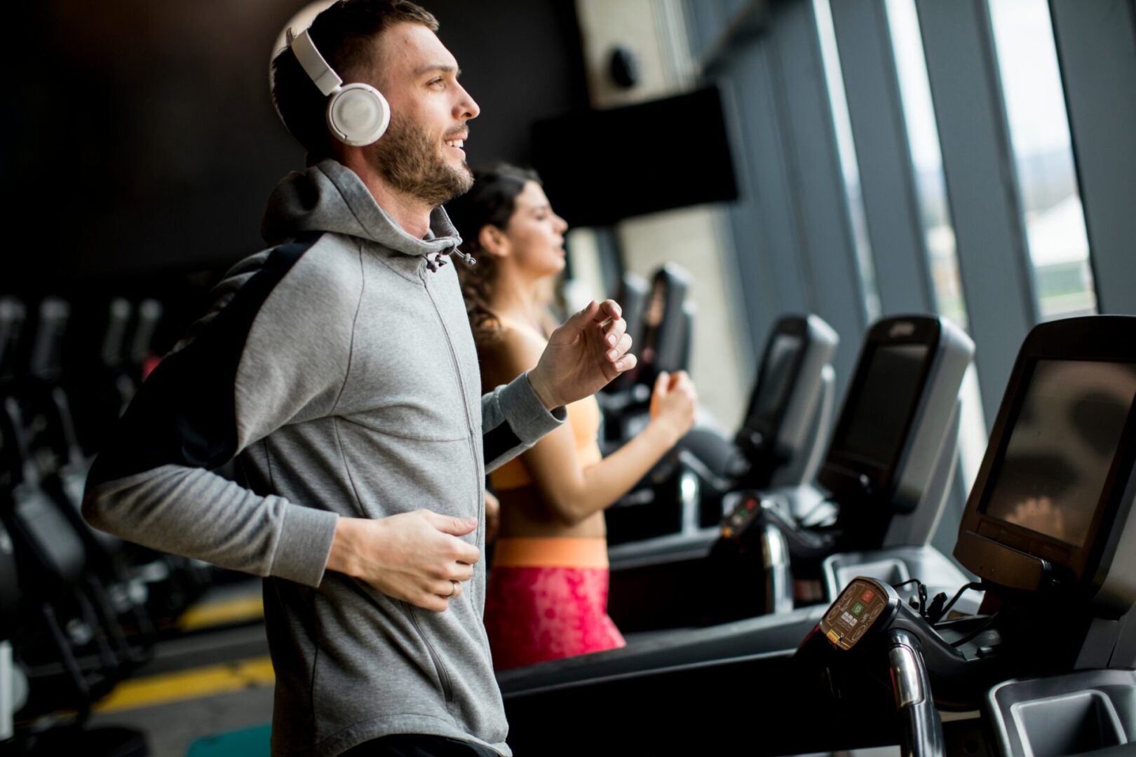 A man and woman jogging on treadmills in a gym.