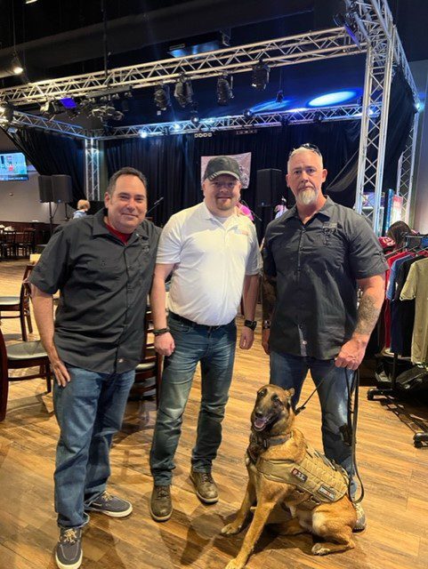 Three men and a dog standing in front of a stage.