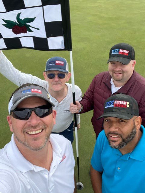 Four people holding a flag at the golf tournament