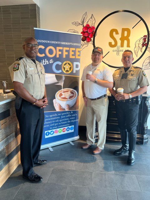 Three men standing in front of a coffee with cop sign.