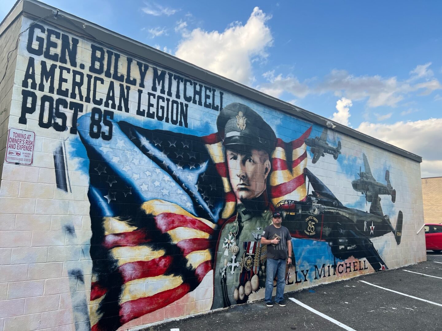 A man standing in front of a mural that says gen billy kitchener american legion post 86.