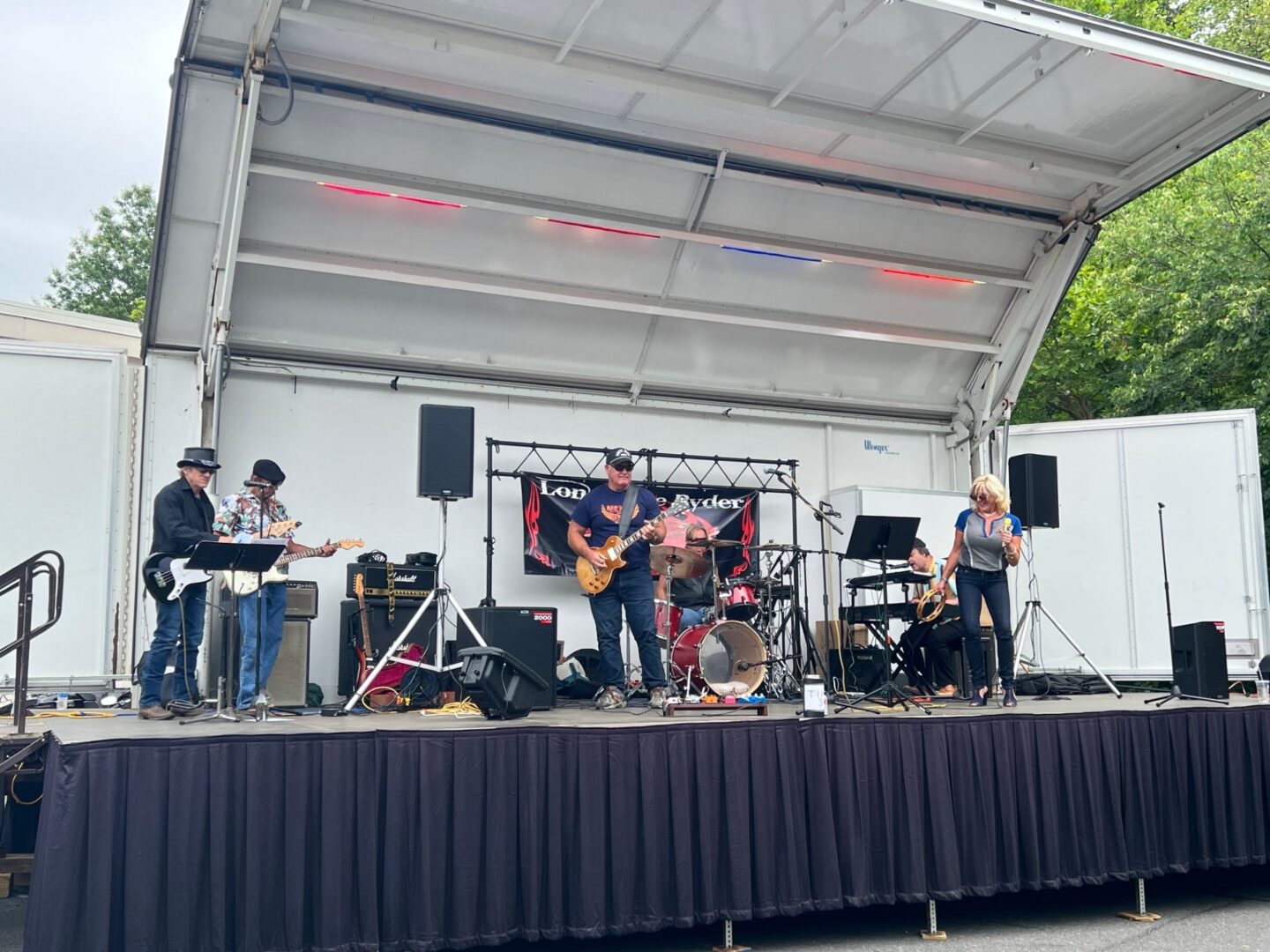 A band performing on stage under a tent.