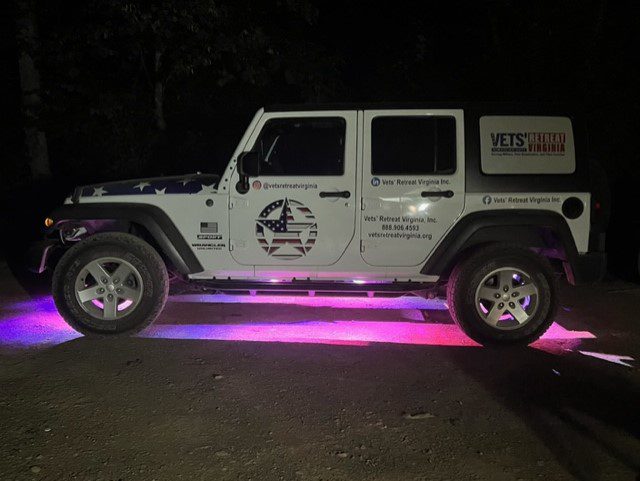 A jeep parked in the dark with pink lights.