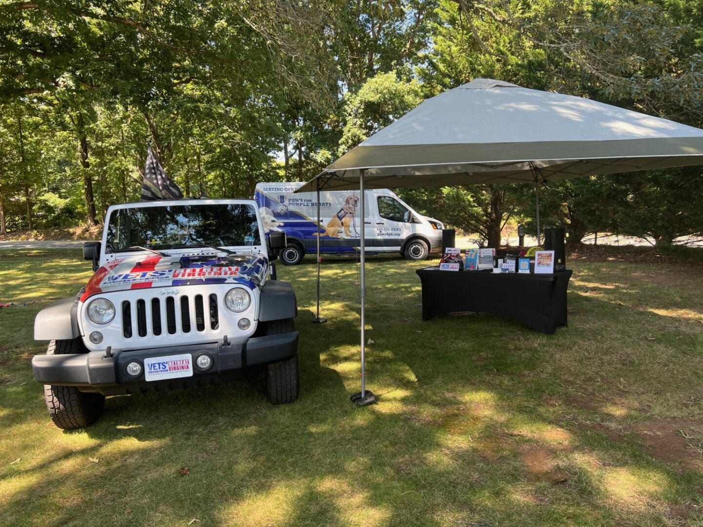 A jeep parked under a tent in a grassy area.