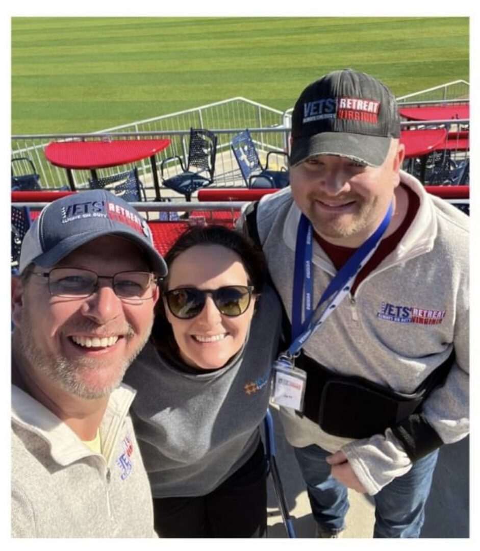 Three people taking a selfie at a baseball stadium.