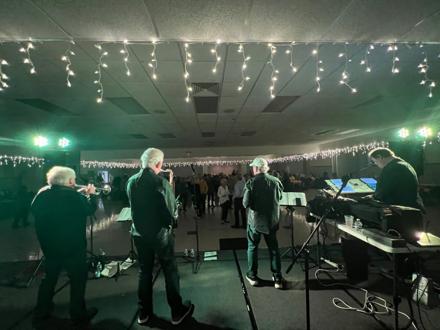 A group of people playing music in a room with lights.