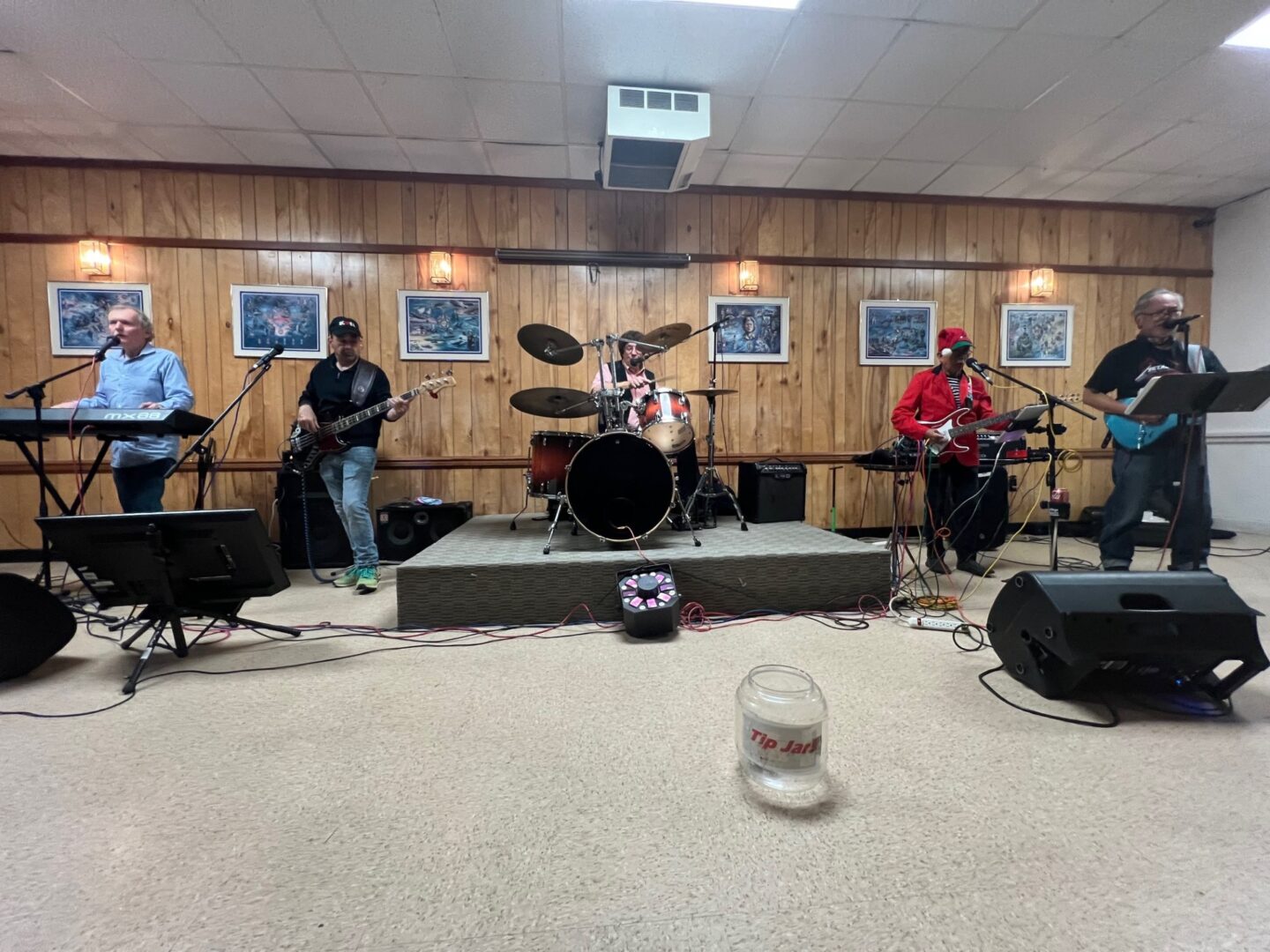 A band performs in a room with wooden walls.