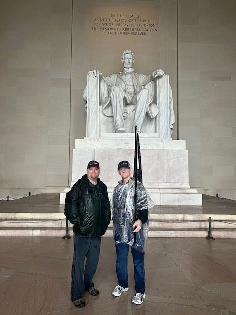 Two men standing in front of a statue.
