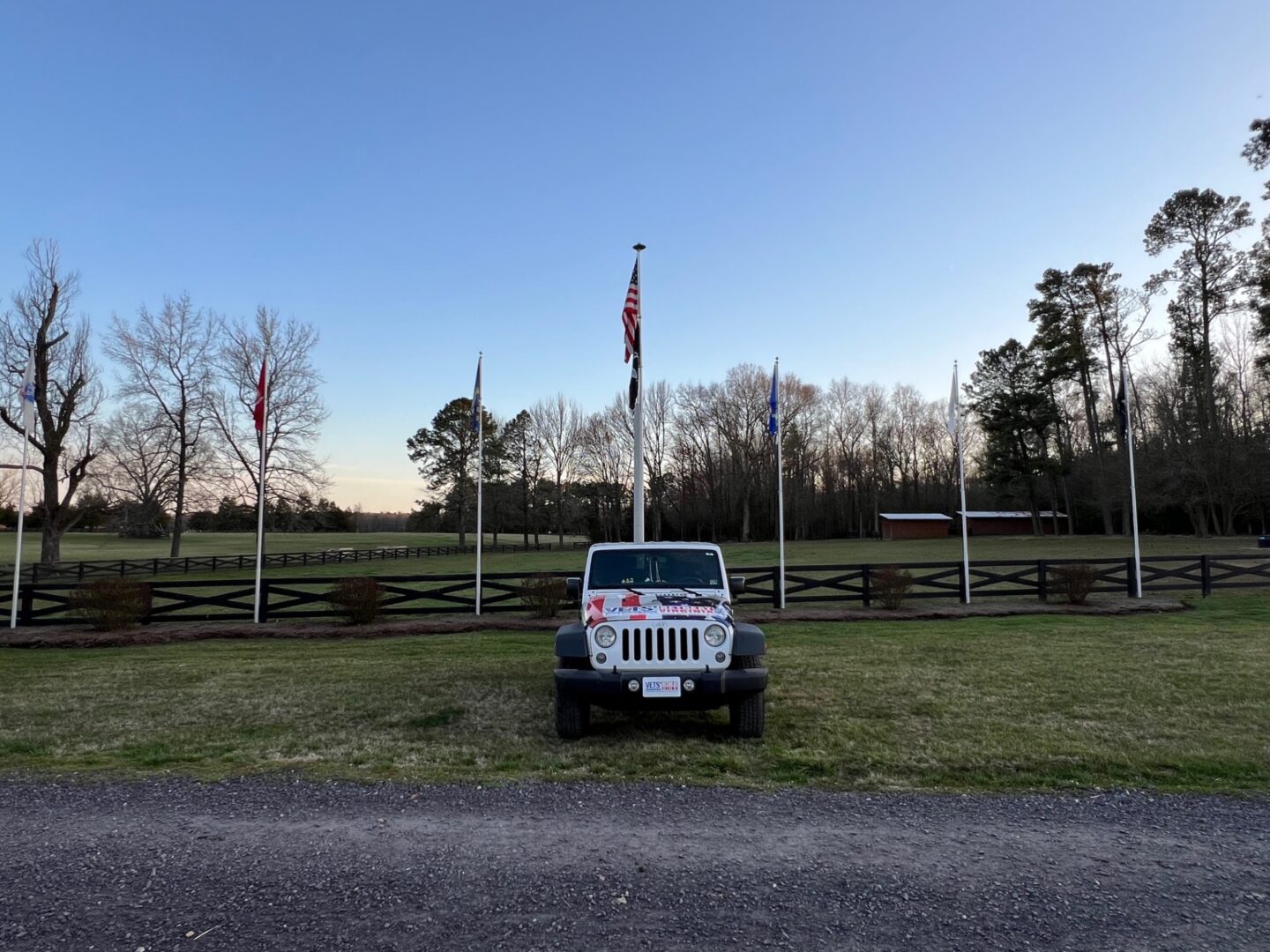 A car standing near a ranch with flags on the back