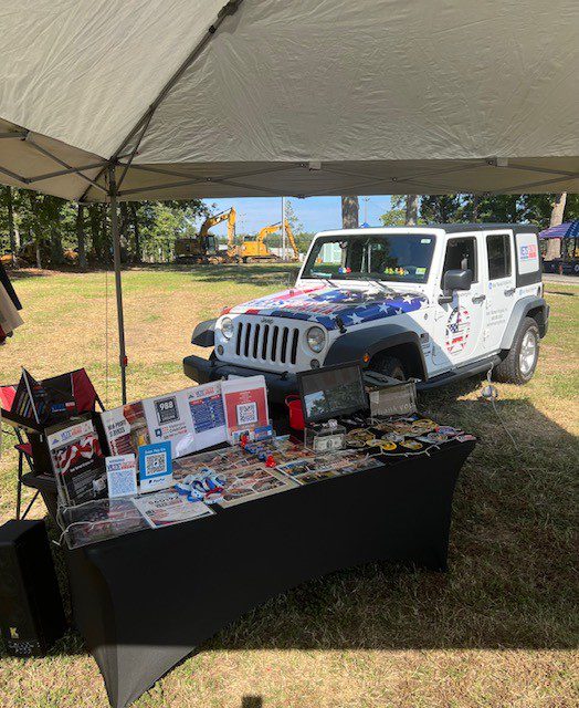 White jeep with American flag at a booth.