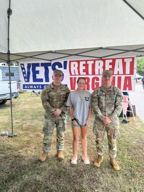 Three veterans pose under a tent.